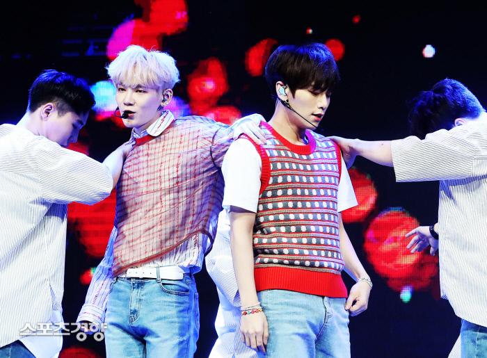 JBJ95のステージパフォーマンス中の姿。メンバーは立体パターンのベストとチェックスリムフィットシャツを着ている。