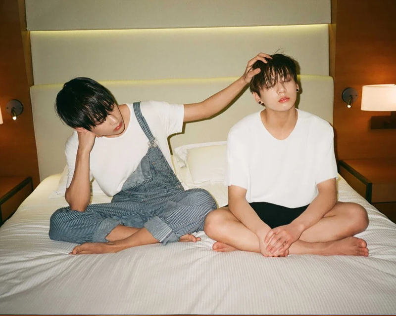 Korean men sitting on bed with legs crossed