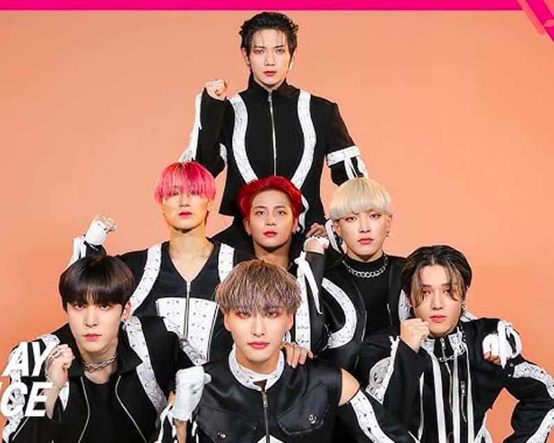 ATEEZ 成員穿著配有白色條紋的黑色服裝，佇立於橙色背景前合照