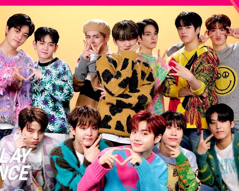 TREASURE 成員穿著鮮豔多彩的毛衣在黃色背景前合影