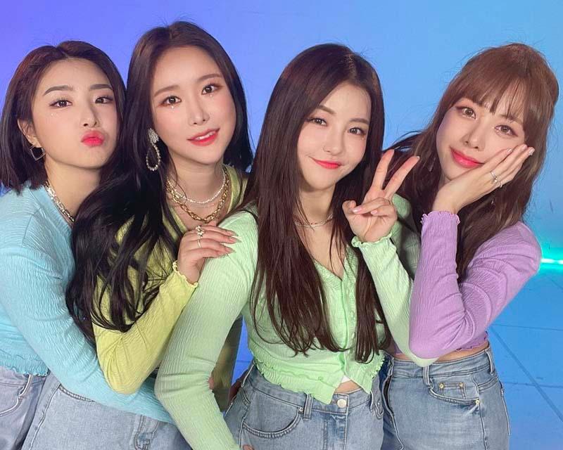 Brave Girls 成員身穿輕便的彩色服裝，以友好姿勢在藍色背景下合影