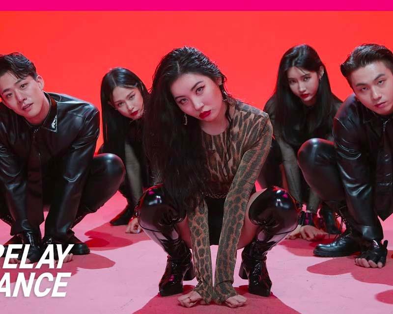 宣美及其同伴們身穿黑色服裝在紅色背景下擺出動感舞姿