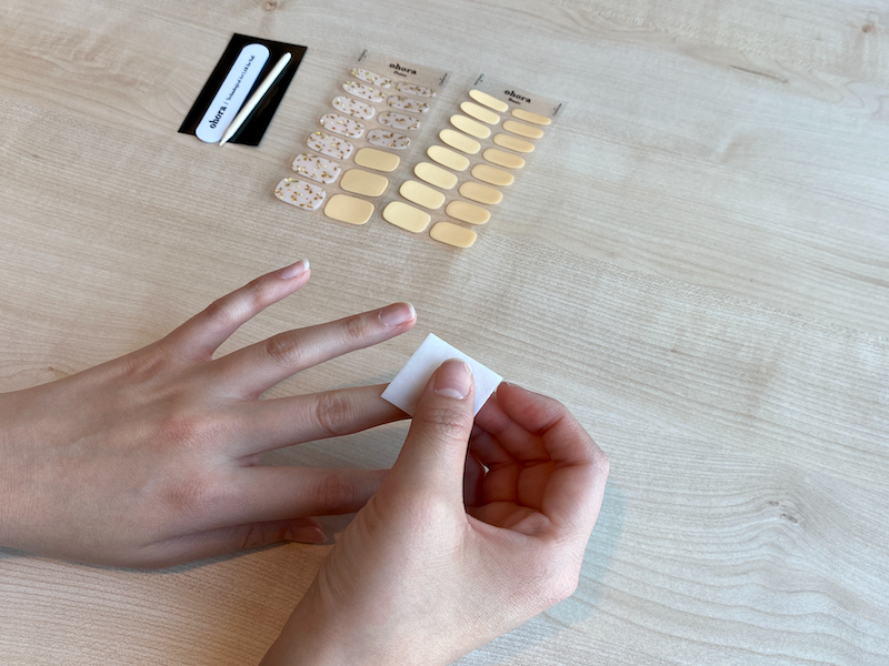 Wiping off excess oil on nails before applying gel nail stickers