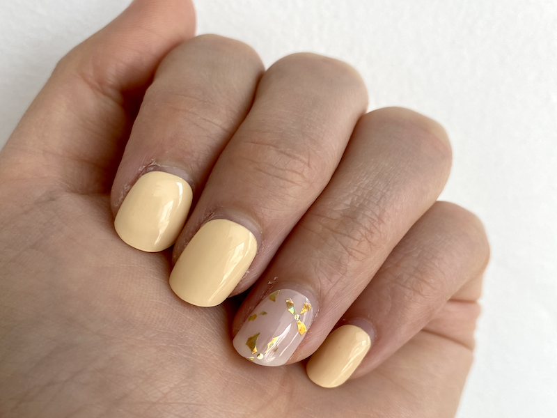 Fotografía de uñas decoradas con pegatinas de una semana de uso, mostrando un diseño primaveral con detalles dorados.