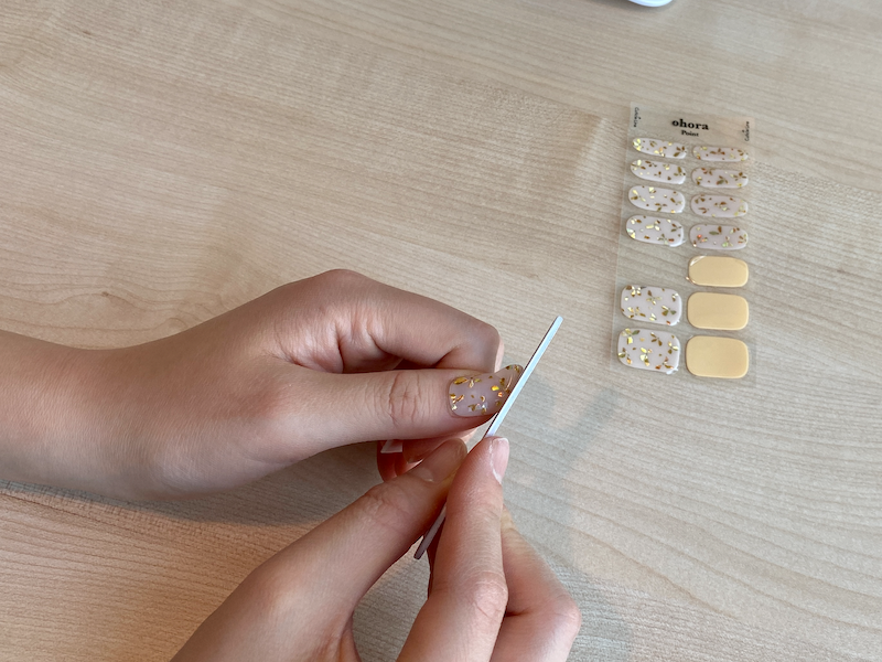 Filing away excess nail sticker from the nail