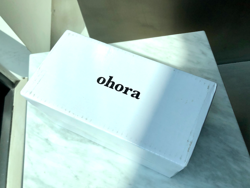 Manos decoradas con pegatinas de uñas de primavera de Ohora, en tonos amarillos y blancos con detalles dorados.