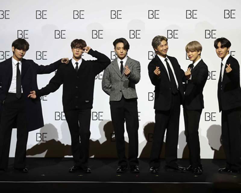 BTS โพสท่าที่มีเอกลักษณ์ในการเปิดตัวอัลบั้ม BE ในงานแถลงข่าว ด้วยชุดสูททางการและแบล็คดรอปที่มีคำว่า BE