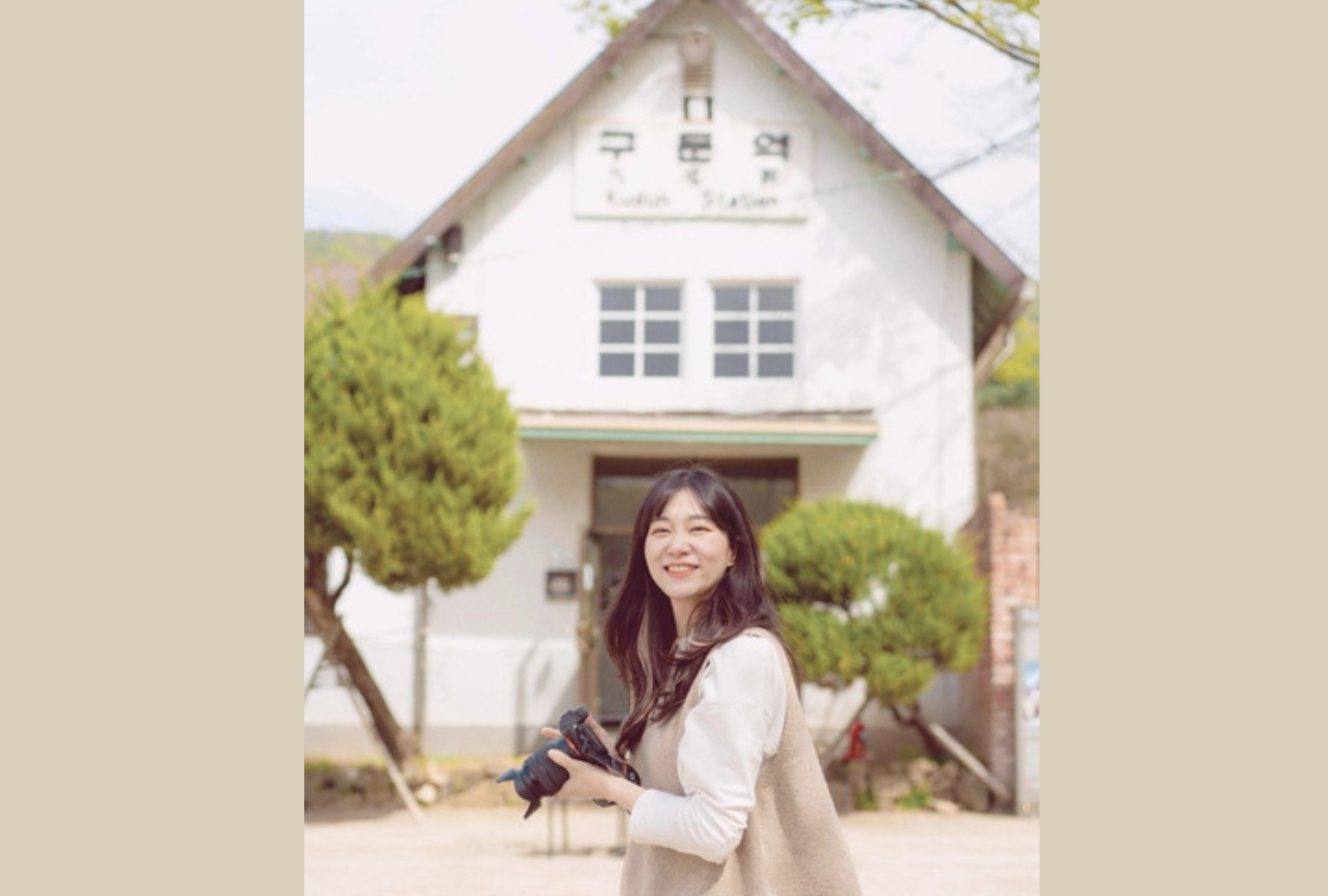 韓国楊平郡の九屯駅を背景にカメラを持っている人物。背景には駅の木造建築が見える。