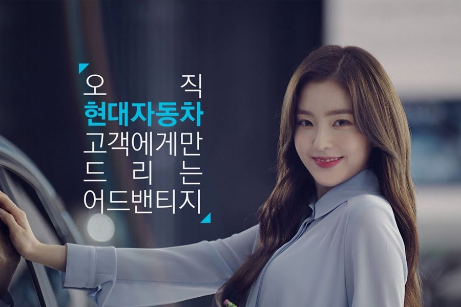 现代汽车广告中展示了女性代言人触摸车身的姿势，背景为夜晚城市环境，突出了品牌的文字广告。