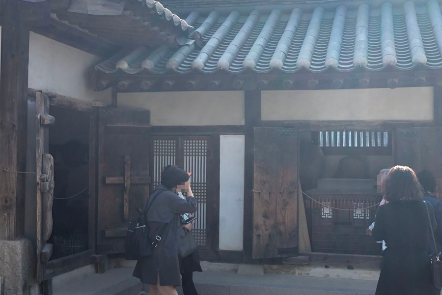 Groups of visitors exploring the courtyard of traditional Korean houses at Namsan Hanok Village.