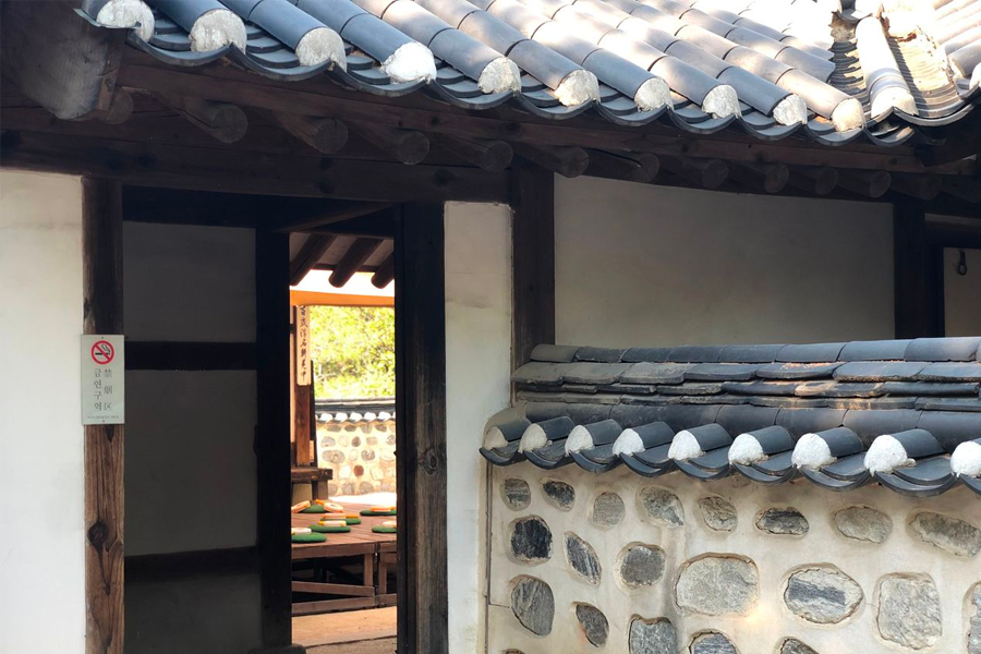 Traditional wooden roofs and tiled walls of Korean hanoks in Namsan Hanok Village vibrant against the green scenery.