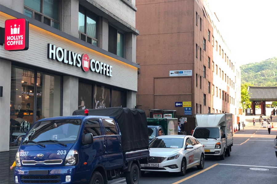 Hollys Coffee shop and adjacent street leading to the entrance of Namsan Hanok Village, Seoul, South Korea.