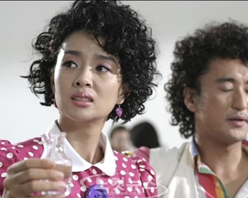 韓國女性身穿粉紅色波點衣物,手持玻璃瓶,説明捲髮的經濟實惠,維持長時間不變形。