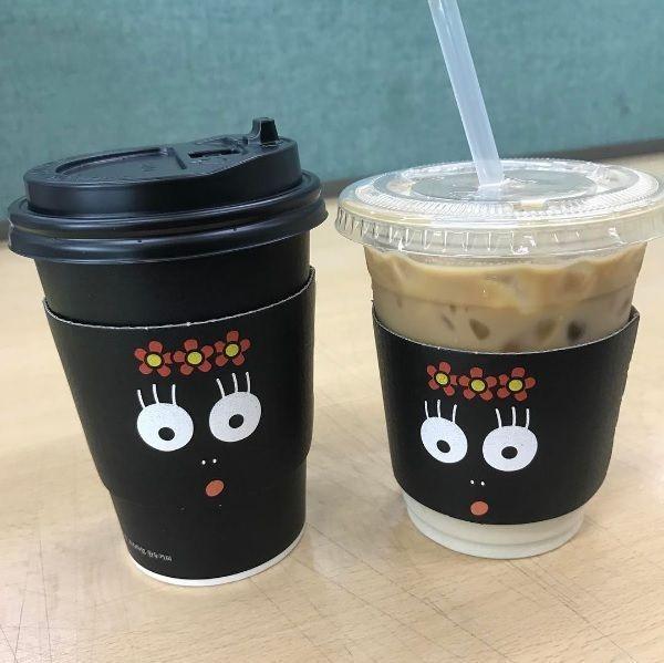블랙 바바파파 커피컵과 투명 컵에 담긴 아이스 커피, 두 컵 모두 귀여운 바바파파 눈동자 디자인으로 시선 사로잡기.