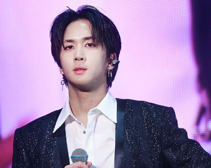 ราวี่ อดีตสมาชิก VIXX ในเสื้อสูทและเสื้อเชิ้ตสีขาวถือายตาในงานถ่ายภาพคอนเสิร์ต