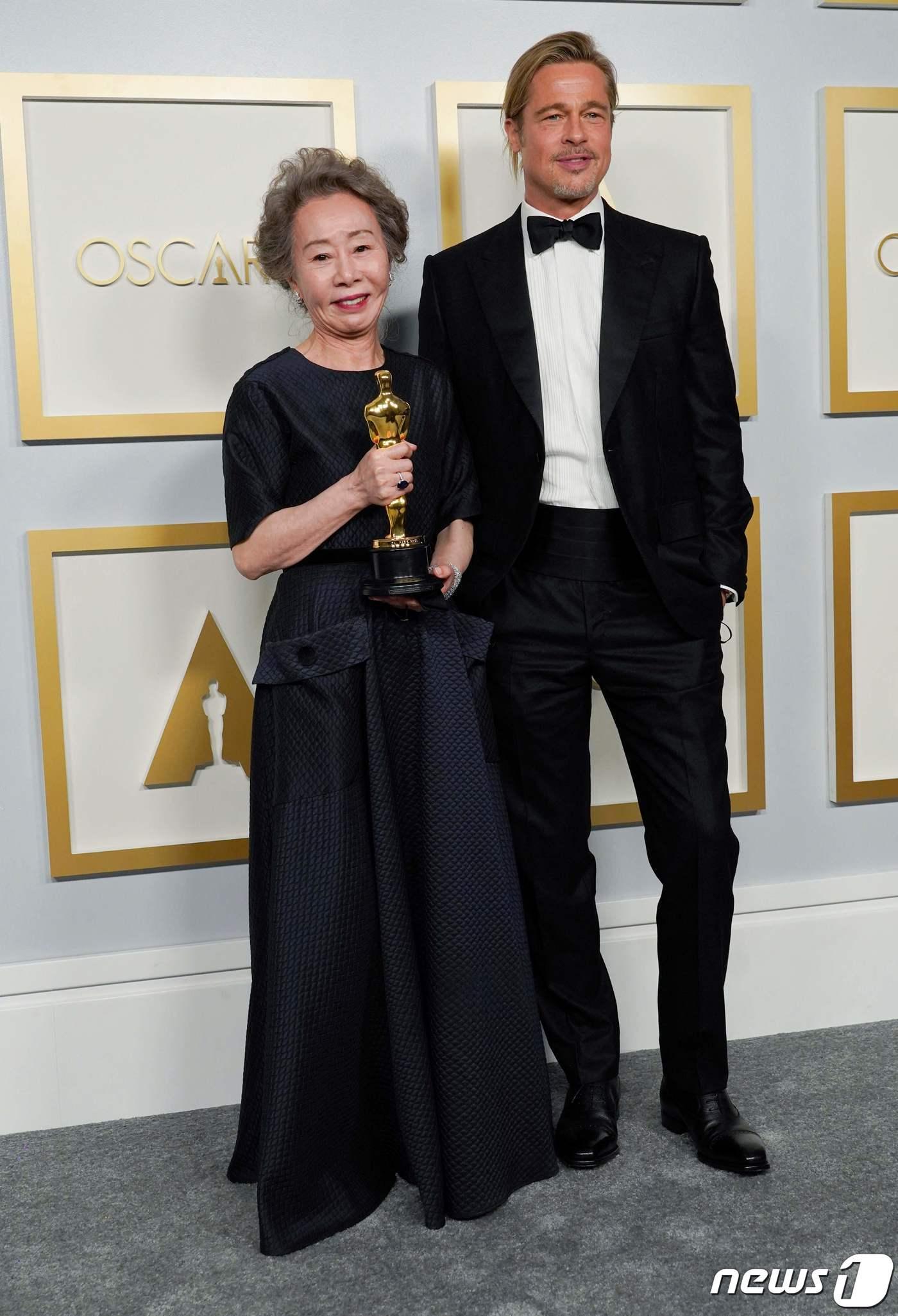ユン・ヨジョンとブラッド・ピットがオスカー授賞式で共に写っている。彼女は受賞トロフィーを手に持ち、彼は黒いタキシードを着用している。