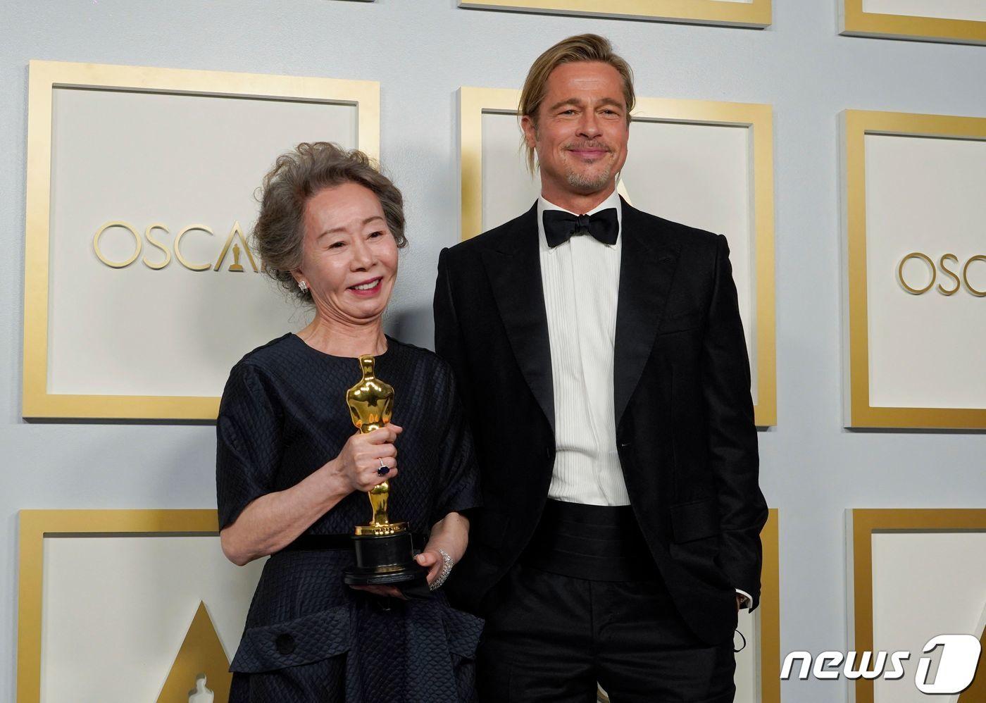 ユン・ヨジョンがオスカー授賞式で俳優ブラッド・ピットと一緒に立っている。彼女はオスカー像を持っておりブラッド・ピットはスーツを着用している。