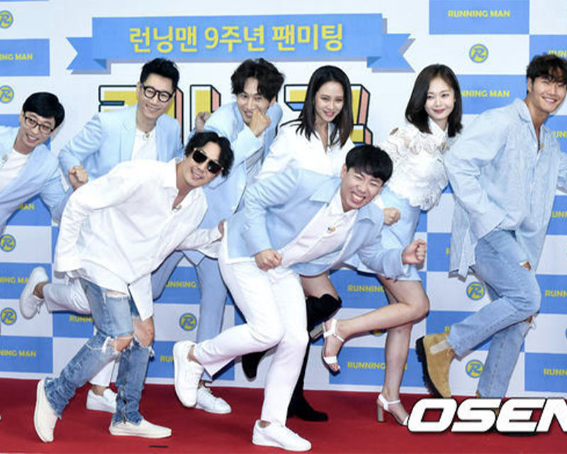 Running Man 成員喺9週年粉絲見面會上合影,成員穿著藍色和白色的服裝,表達出節目的活力與幽默氛圍。