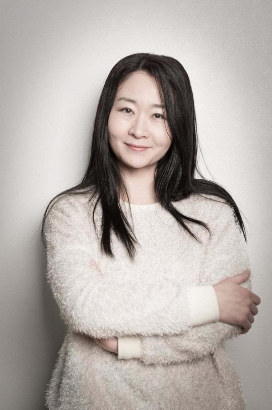 白いセーターを着て腕を組んで立つ女性