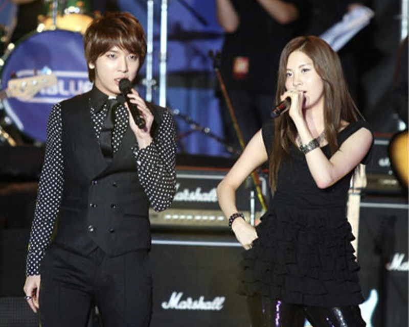 韓國綜藝《我們結婚了》“紅薯夫婦”在舞台上演唱，他們身穿黑色服裝，手持麥克風