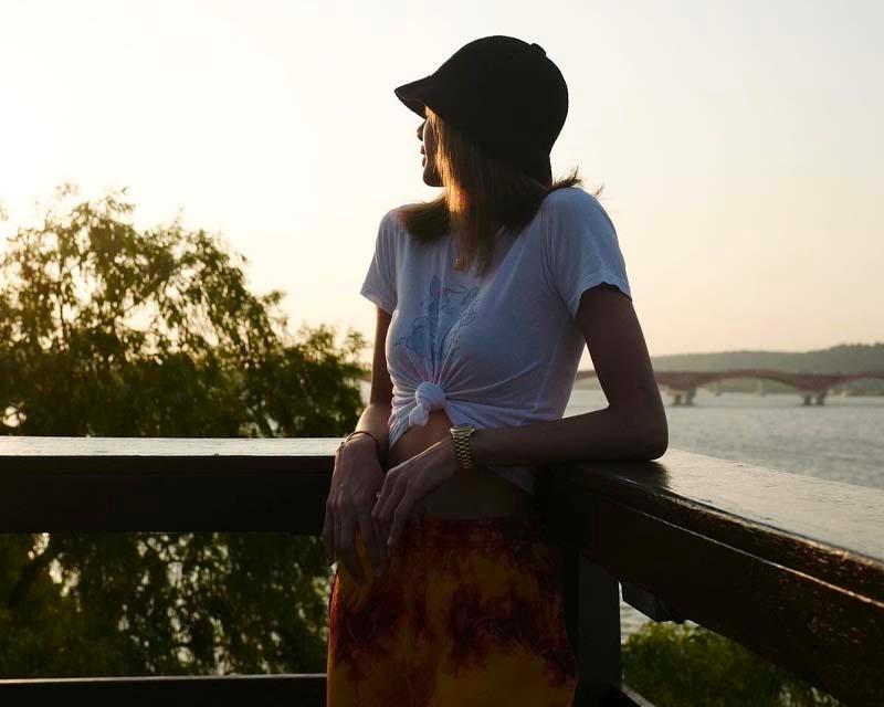 หญิงสาวเกาหลีในชุดเสื้อผูกเอวสีขาวและหมวกโคลชสีดำ ท่ามกลางบรรยากาศยามเย็นริมสะพานไม้