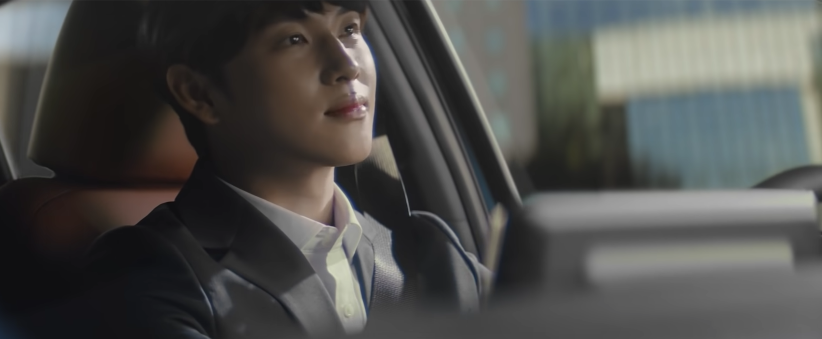 未生2021广告中驾驶汽车的上班族画面，展示KIA新款K3车内设计的现代感。