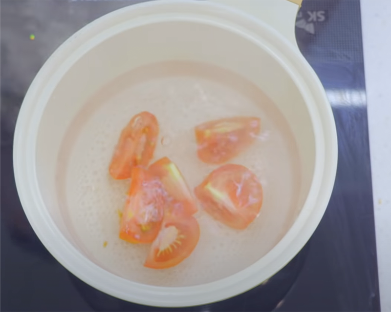 Putting pieces of tomatoes into boiling water for NCT Chenle