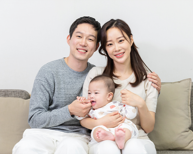 man and woman sitting on couch with a newborn baby