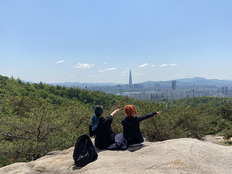 Two women pointing on Achasan with a view of the Lotte Tower