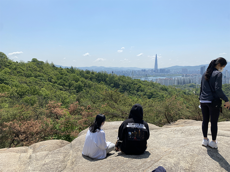 Seoul locals sitting on the bed of rock overlooking the view of the city on Achasan