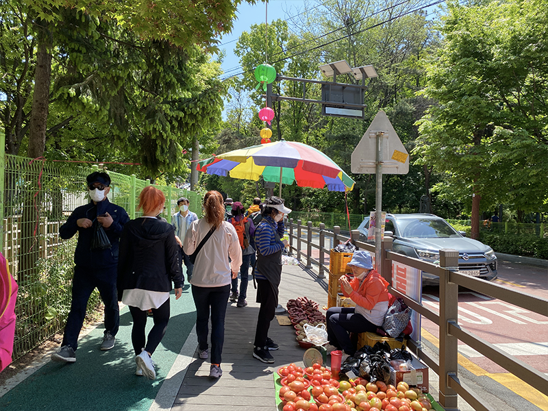 韓國街市的人們在路邊安靜地行走，小販和展示的商品增添了此地的市集氛圍。