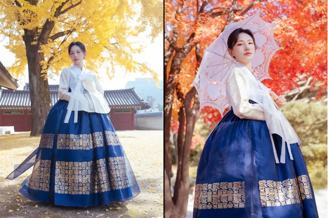 穿著深藍金紋韓服的遊客在景福宮內拍照：左側銀杏樹與宮殿屋瓦映襯，右側以紅葉與蕾絲陽傘營造秋季韓服外拍氛圍，凸顯夜間或季節行程推薦。