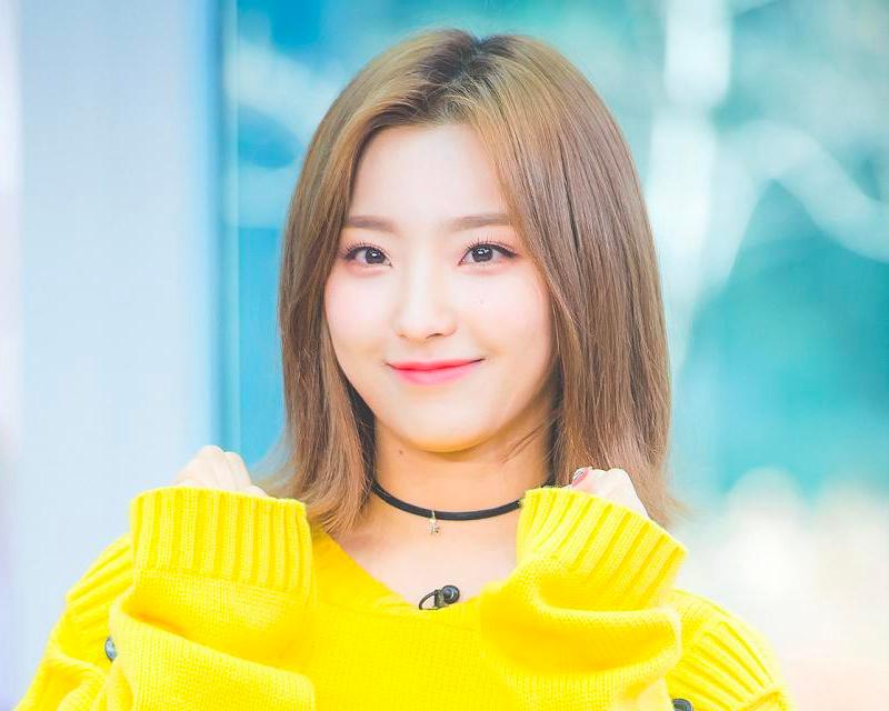 fromis_9賽綸穿著藍色條紋毛衣，靠在牆壁上，背景是獎盃及音樂光碟牆，展現出酷炫形象。