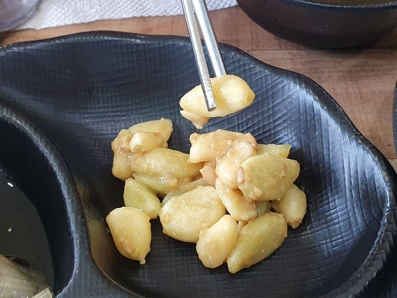 garlic on a black plate being held with chopsticks at Dawon Restaurant Danyang