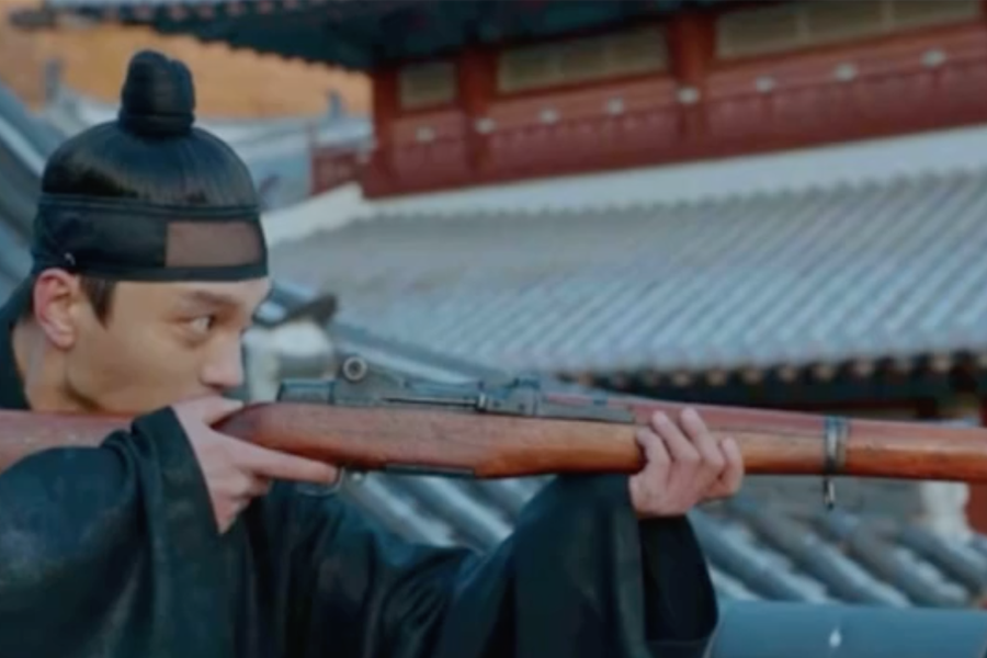 一名穿著韓國古裝的角色手持步槍，背景是傳統韓國宮殿屋頂。這個場景來自韓國電視劇《哲仁皇后》，劇中時代背景與現代武器不符，成為一個有趣的穿幫場景。