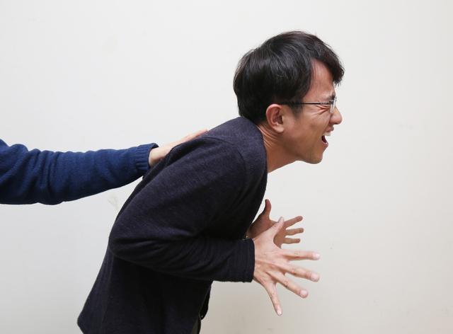 兩個人的互動情況,其中一人正在用手推另一個人,背景是白色牆面。