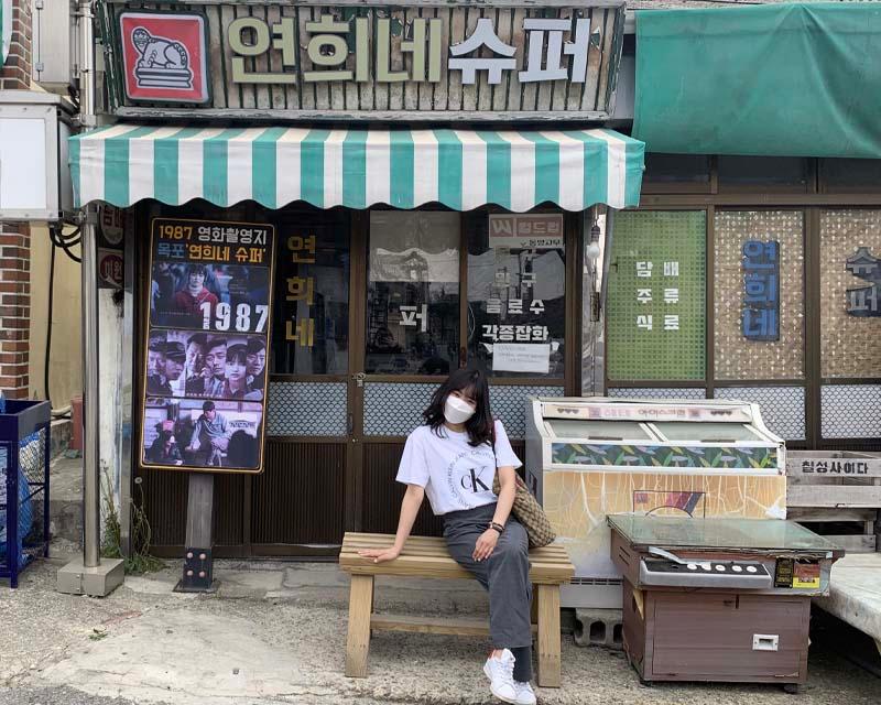 在木浦詩畫村中，遊客坐在《1987：逆權公民》拍攝場景附近的一個小超市前休憩。