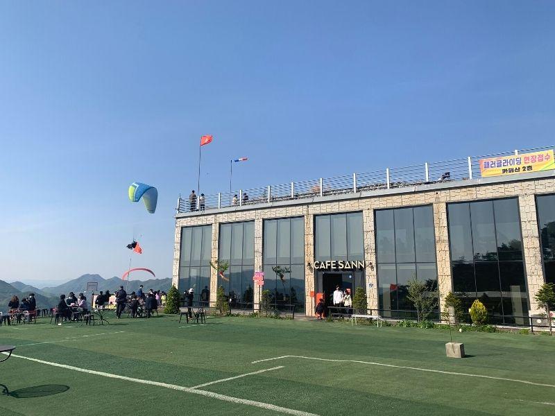 ouside view of cafe sann in danyang with lots of people and paragliders