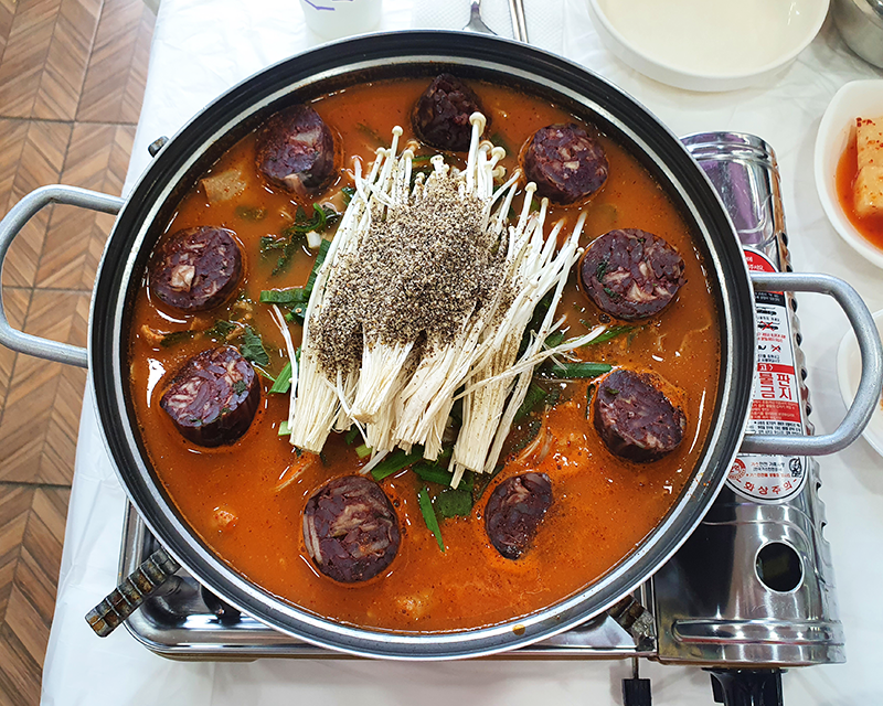 garlic sundae giblets hotpot with sundae, gopchang, and mushrooms on portable gas stove at Chungcheongdo Sundae in danyang south korea