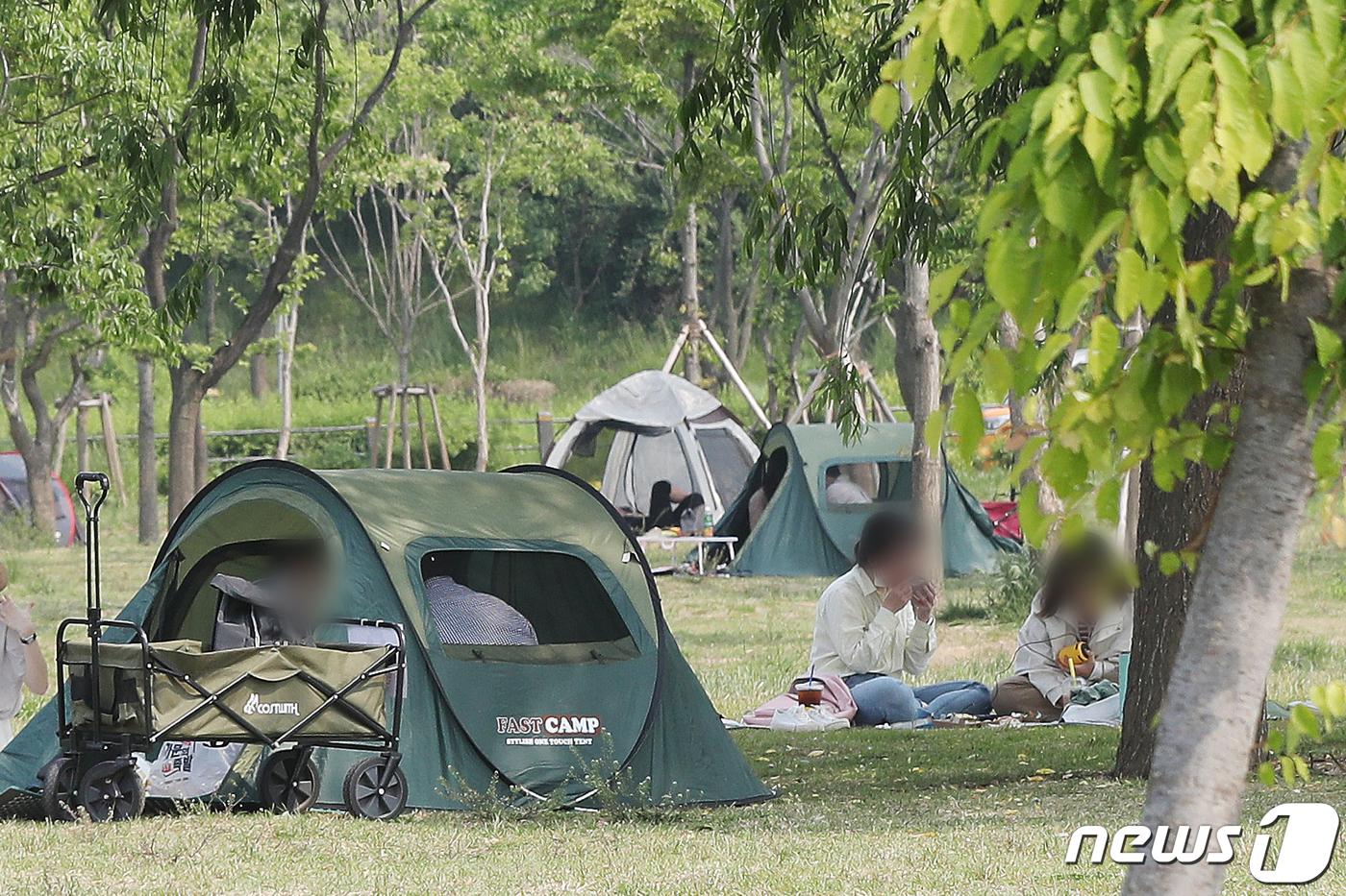 ソウル市の盤浦漢江公園で、市民たちがテント内で集まり、ピクニックを楽しむ様子。2021年5月中旬、新型コロナウイルスの影響での屋外活動の制約が議論されています。