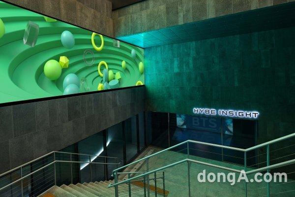  HYBE 인사이트의 입구, 녹색 조명과 원형 장식이 있는 내부 계단.