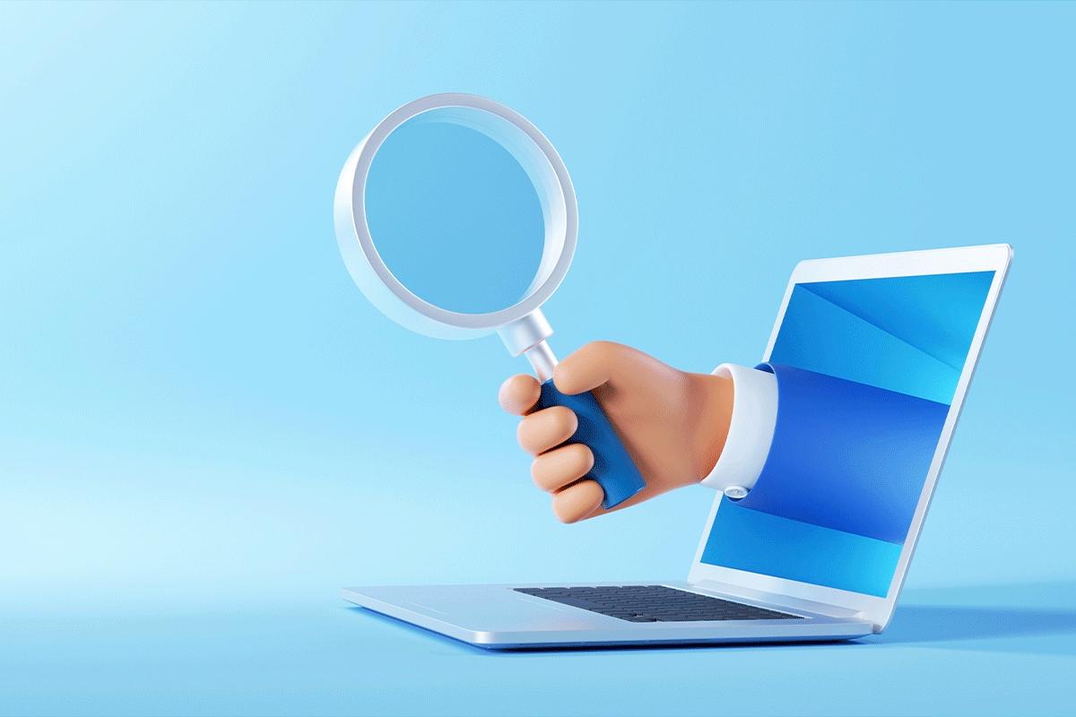 hand holding a magnifying glass coming out of a laptop screen