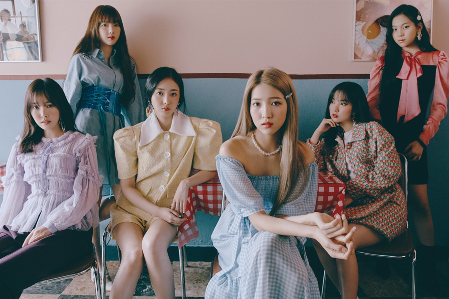 GFRIEND成員合照，穿著時尚的裙裝和襯衣，坐在室內的桌子旁，展現韓國人氣女子組合的獨特風格