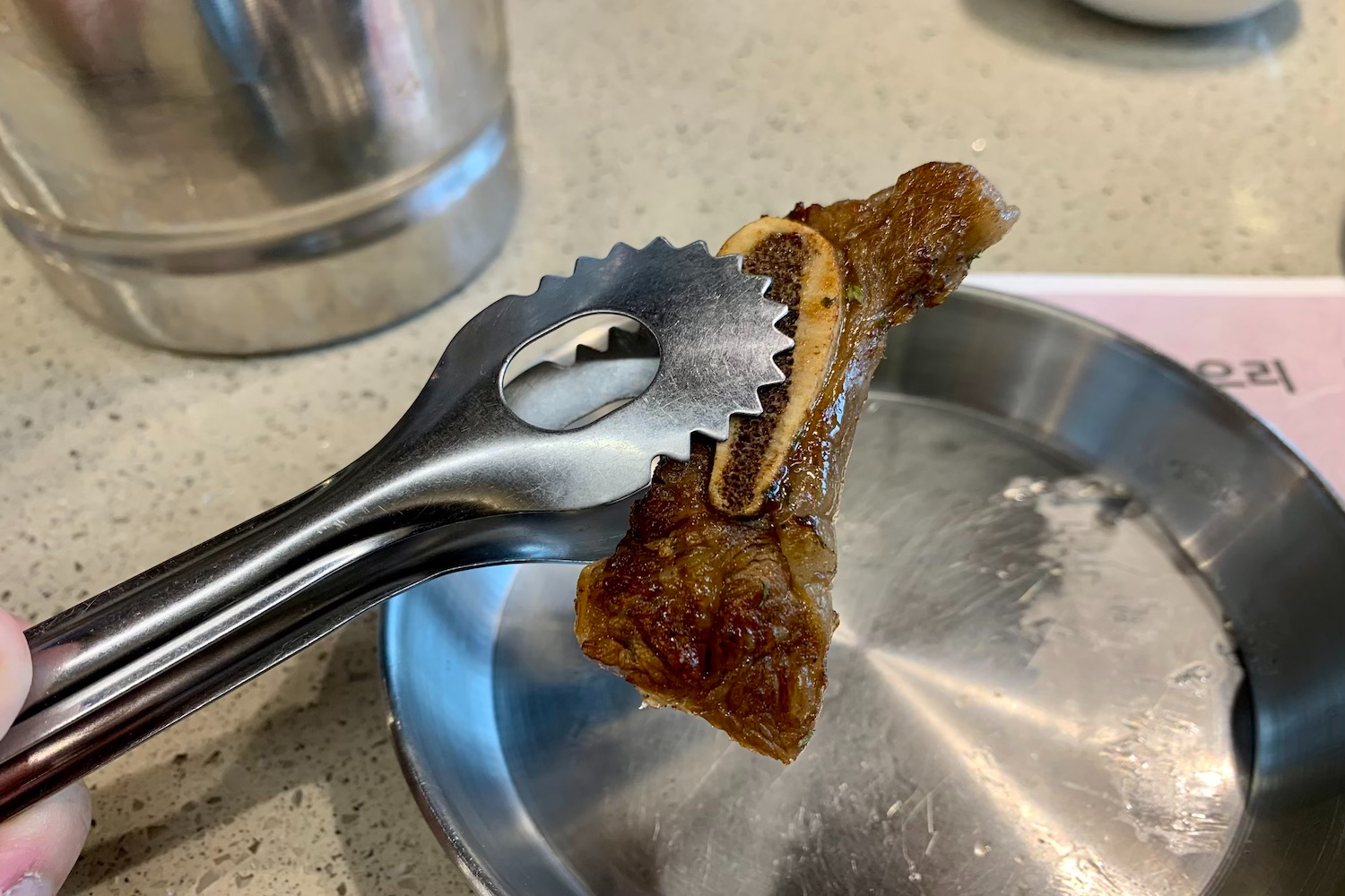 meat being held with silver tongs at Yangban Galbi Daegu