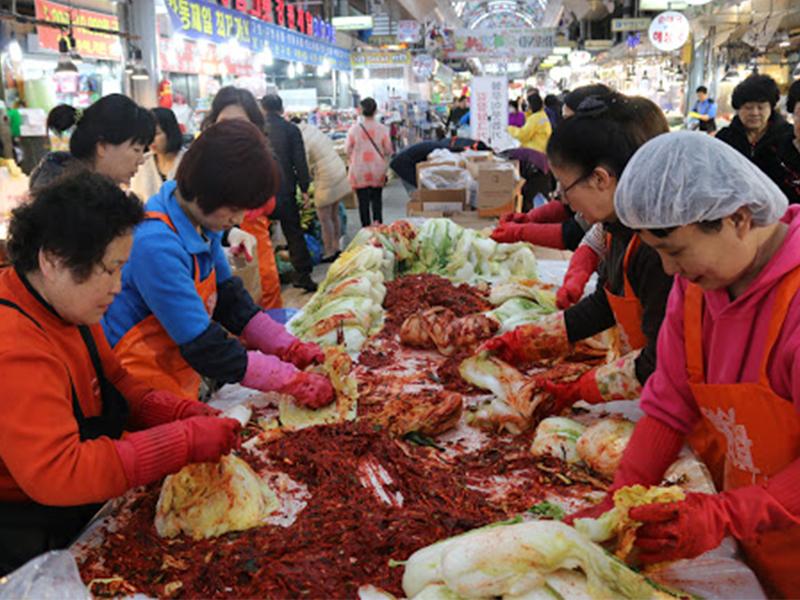 在市場中的韓國婦女們正在一起醃製泡菜,這是一種代表韓國情感文化的集體行為。