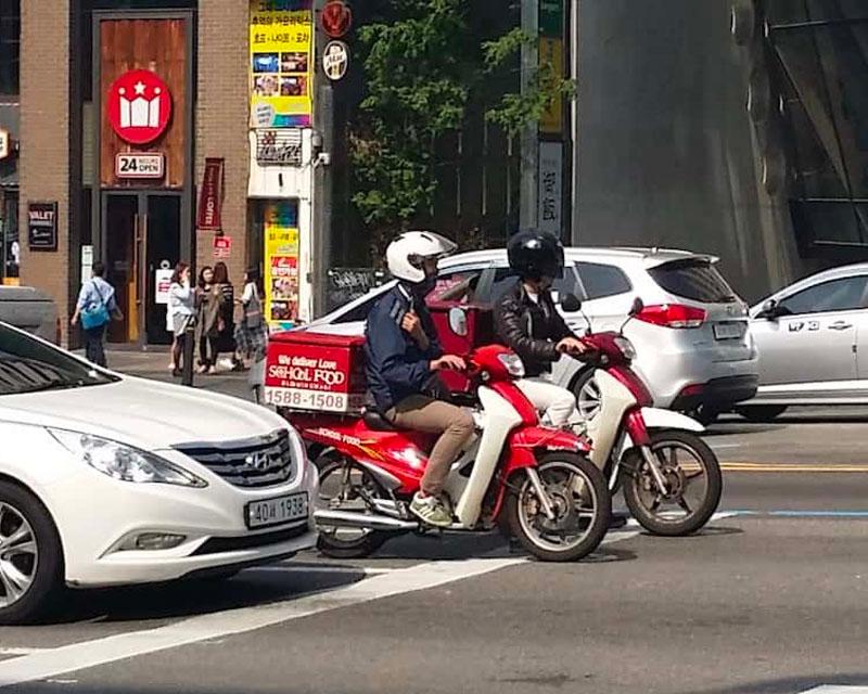 รถมอเตอร์ไซค์เดลิเวอรีขี่บนถนนในเมืองเกาหลี