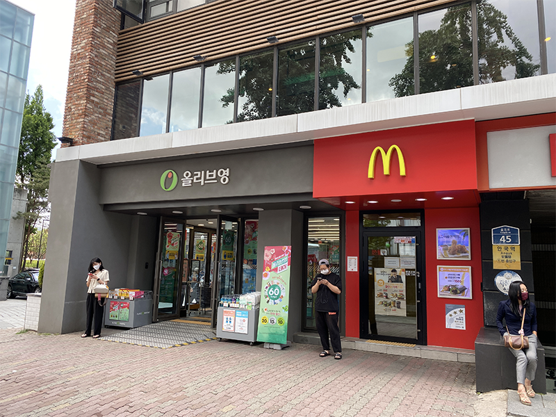 Entrance of Olive Young and McDonald's near Anguk Station with people standing outside, indicating the location of popular stores in Seoul.