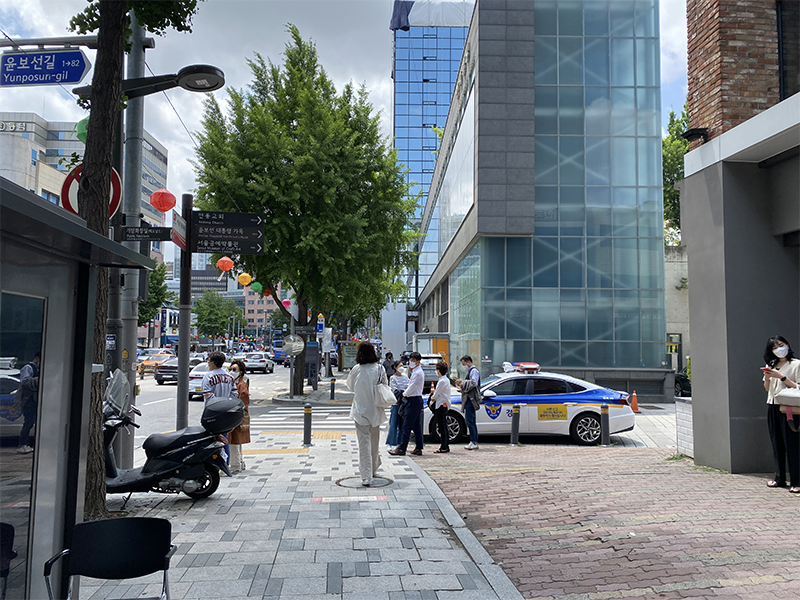 Bustling street view near Olive Young and McDonald's showcasing a busy intersection with trees and tall buildings in Seoul, Korea.