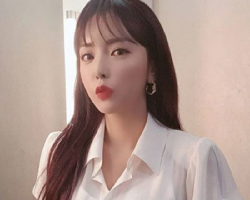 韓國藝人洪真英的照片，身穿白色襯衫，背景為現代辦公室。