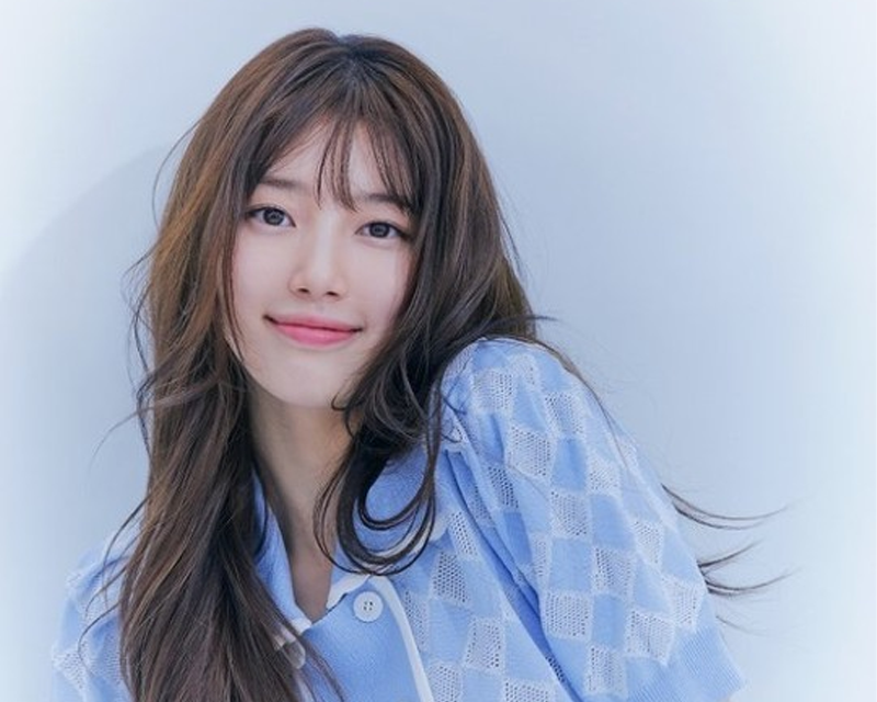 韓國藝人秀智的照片，穿著淺藍色連衣裙，背景為淺藍色。